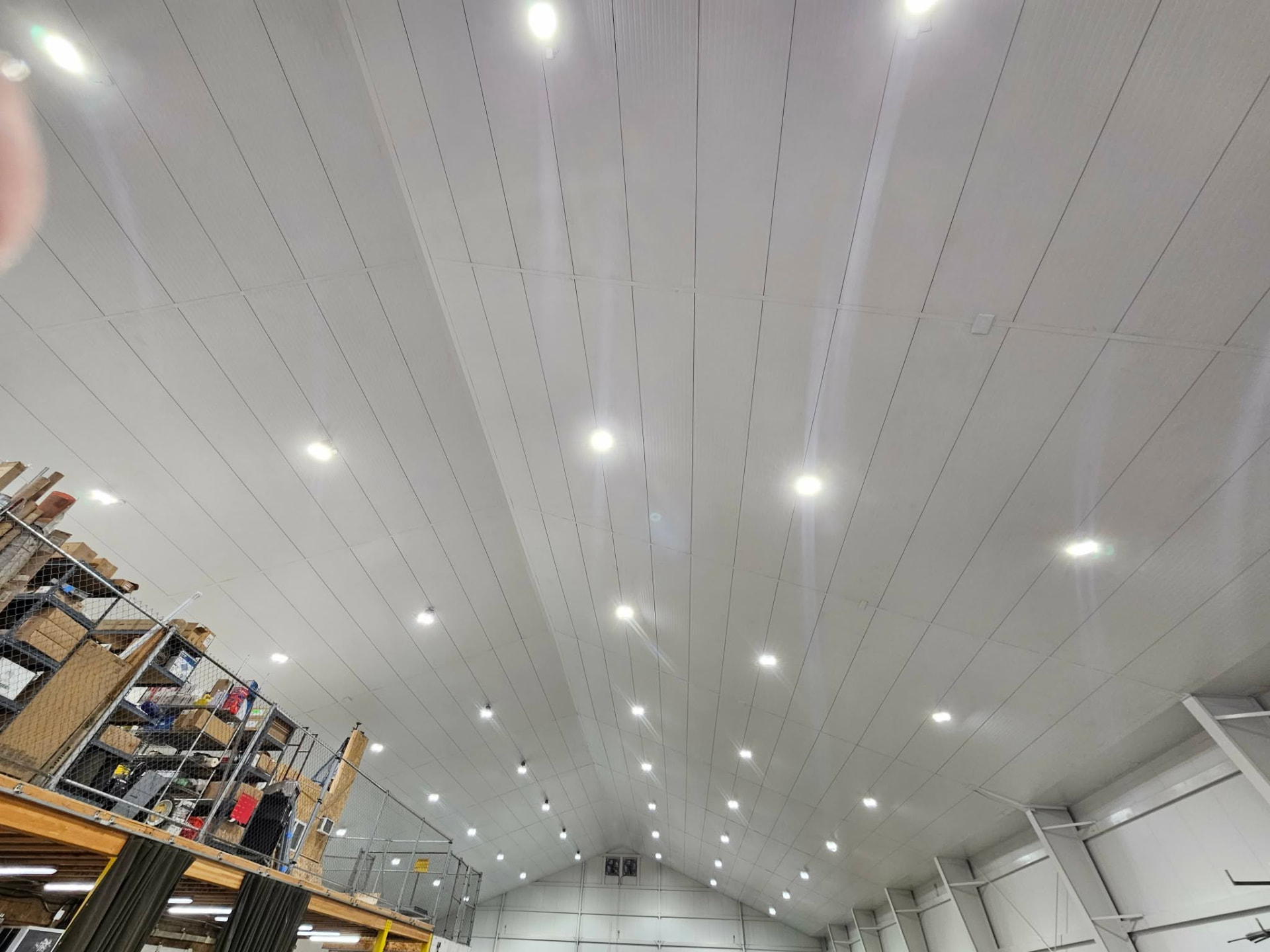Completed white commercial ceiling panels with evenly spaced round overhead lights