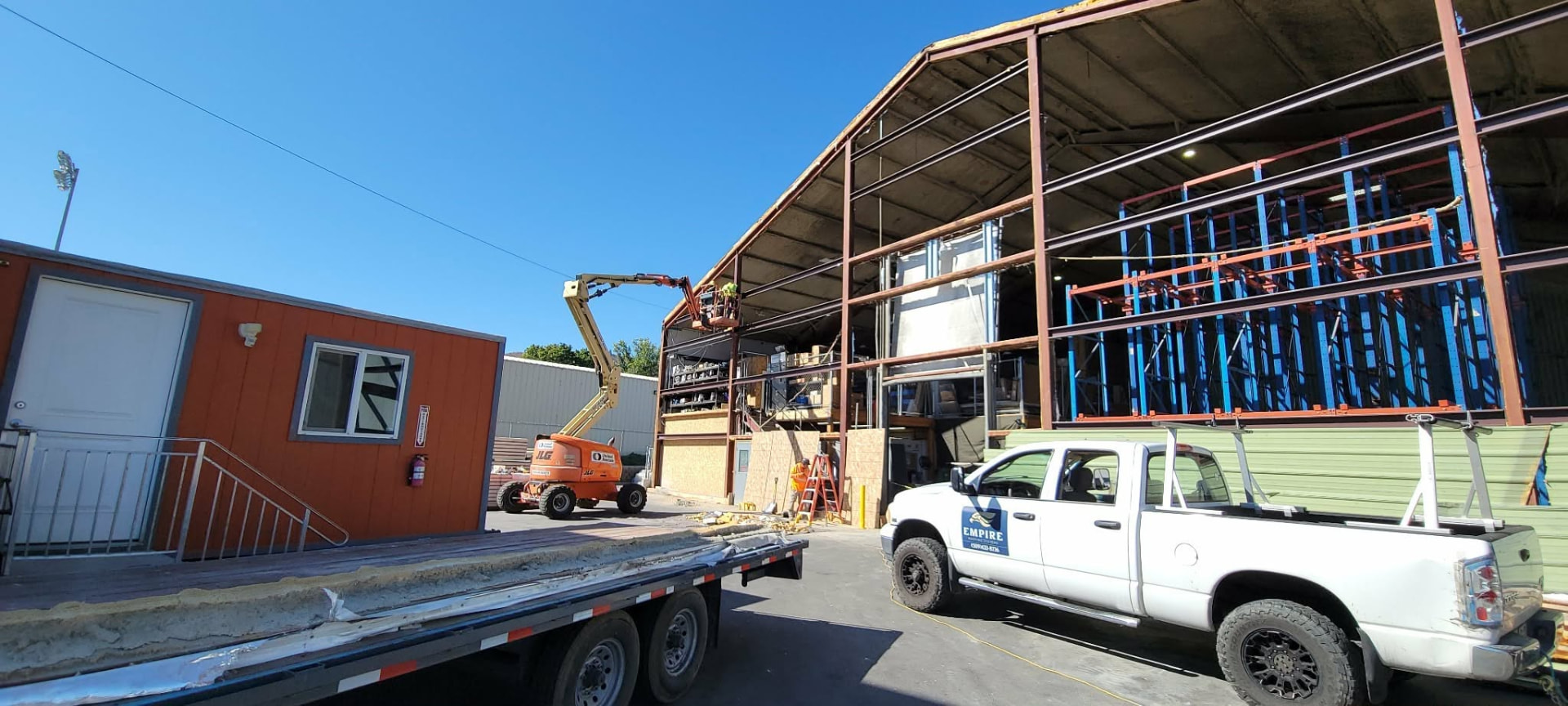 Empire Roofing Systems truck beside a commercial building where the crew is working from a boom lift